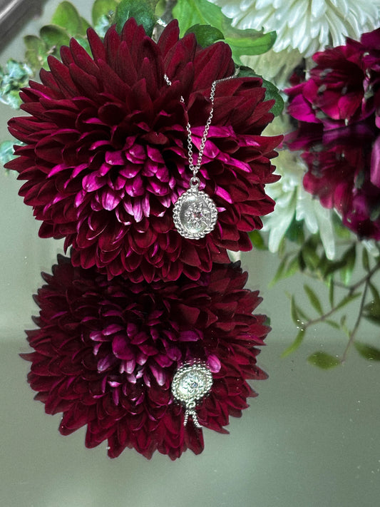 Necklace with a pendant displayed on maroon flowers against a light background