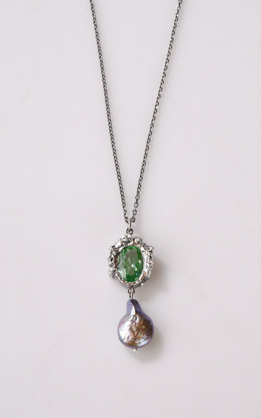 Necklace with green gemstone and silver pendant with purple baroque pearl on a white background