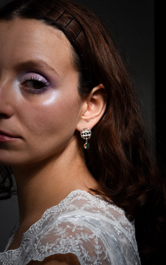 Close-up of a woman wearing a silver earring with a dark background