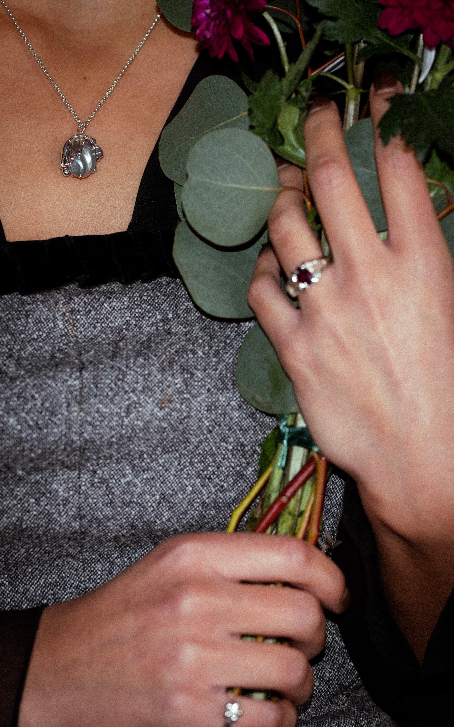 Person holding a bouquet of flowers with a close-up of hands and jewelry.