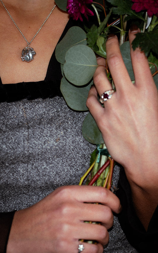 Person holding a bouquet of flowers with a close-up of hands and jewelry.