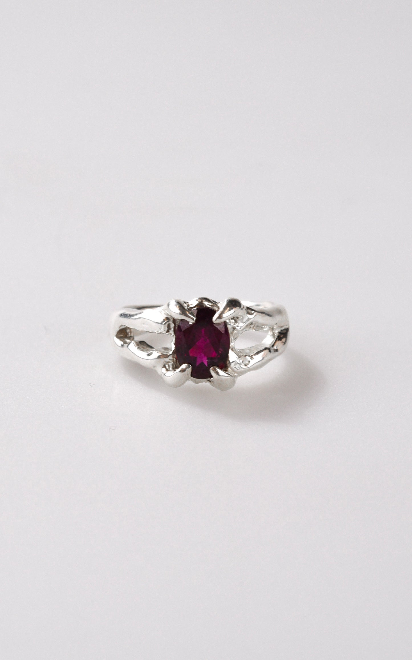 Silver ring with a burgundy maroon gemstone on a white background