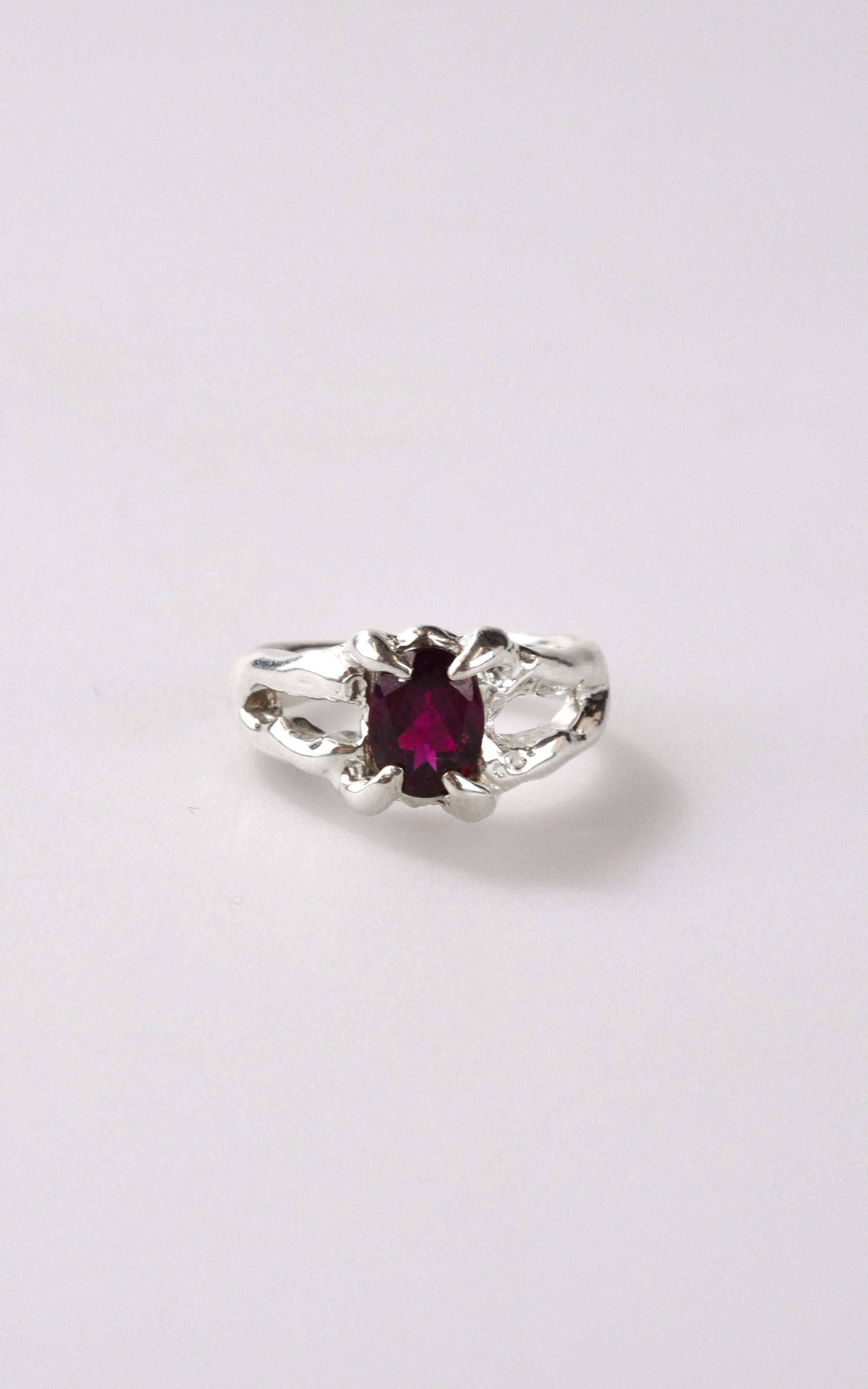 Silver ring with a burgundy maroon gemstone on a white background