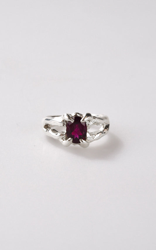 Silver ring with a burgundy maroon gemstone on a white background