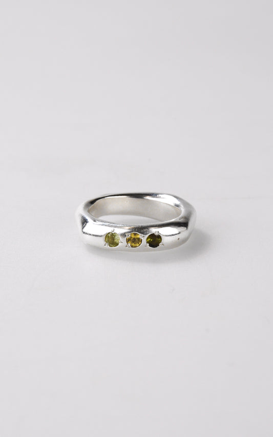 Handmade silver ring with three small tourmaline stones on a light gray background