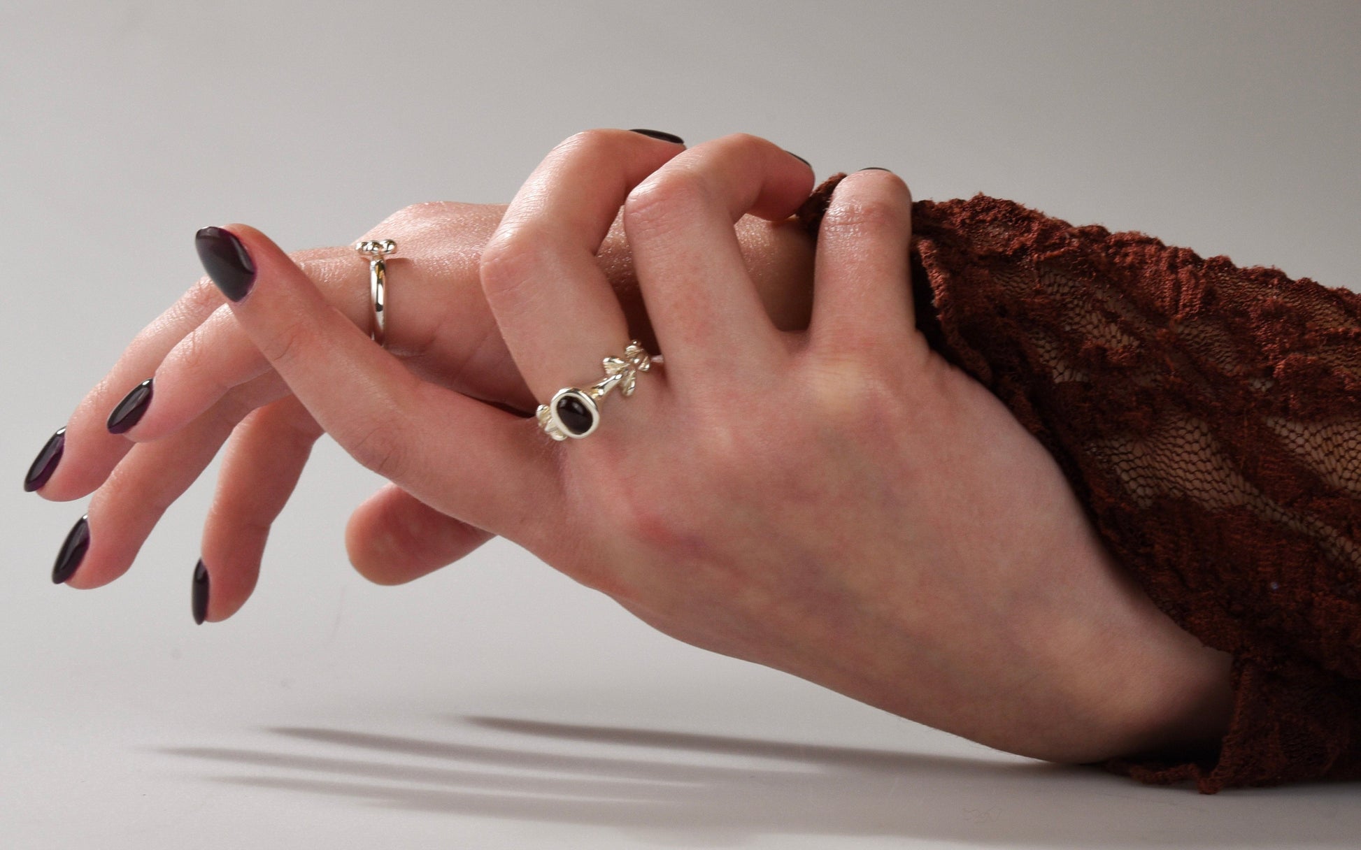 Close-up of a hand wearing two rings with a neutral background