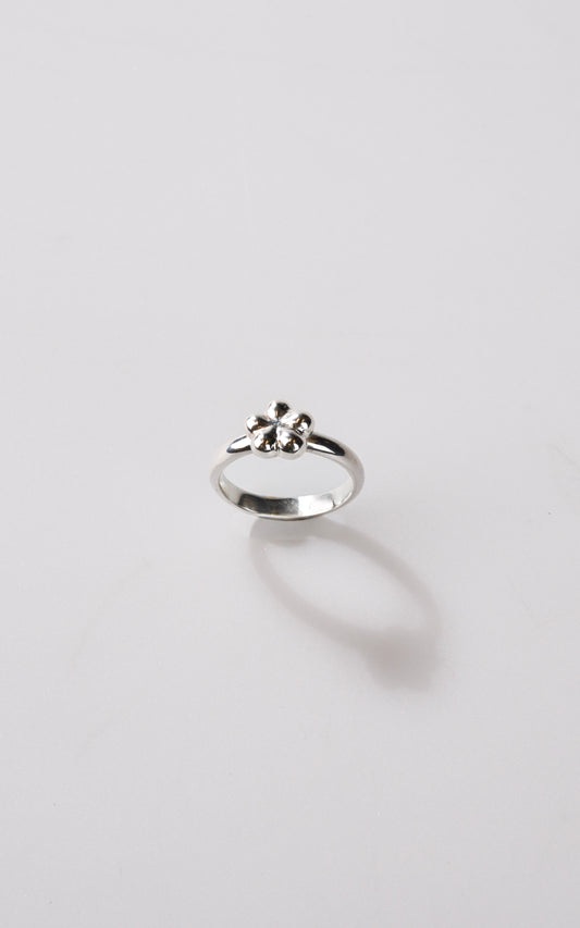 Silver ring with a small flower design on a light gray background