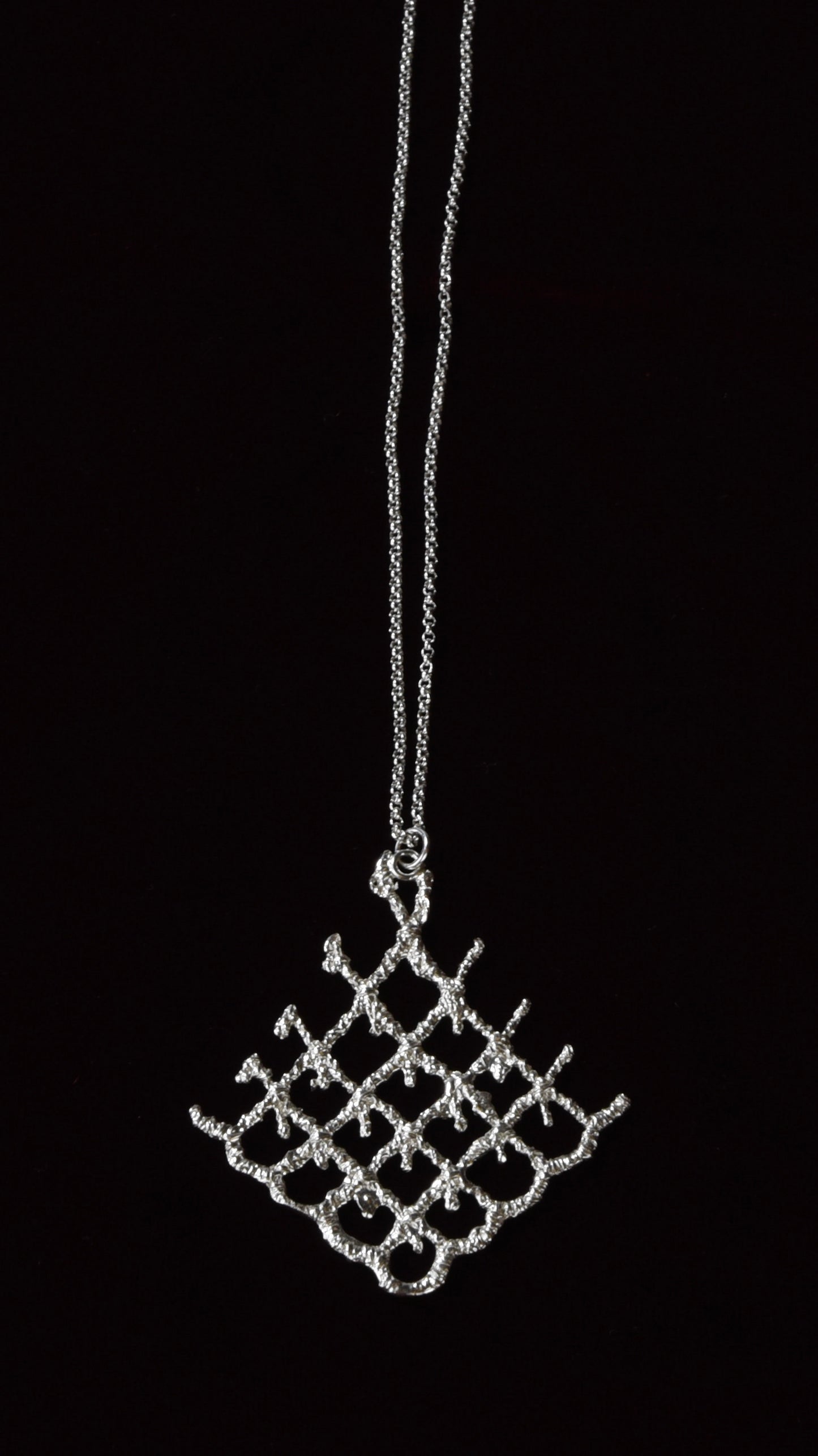 Silver lattice pendant necklace on a black background