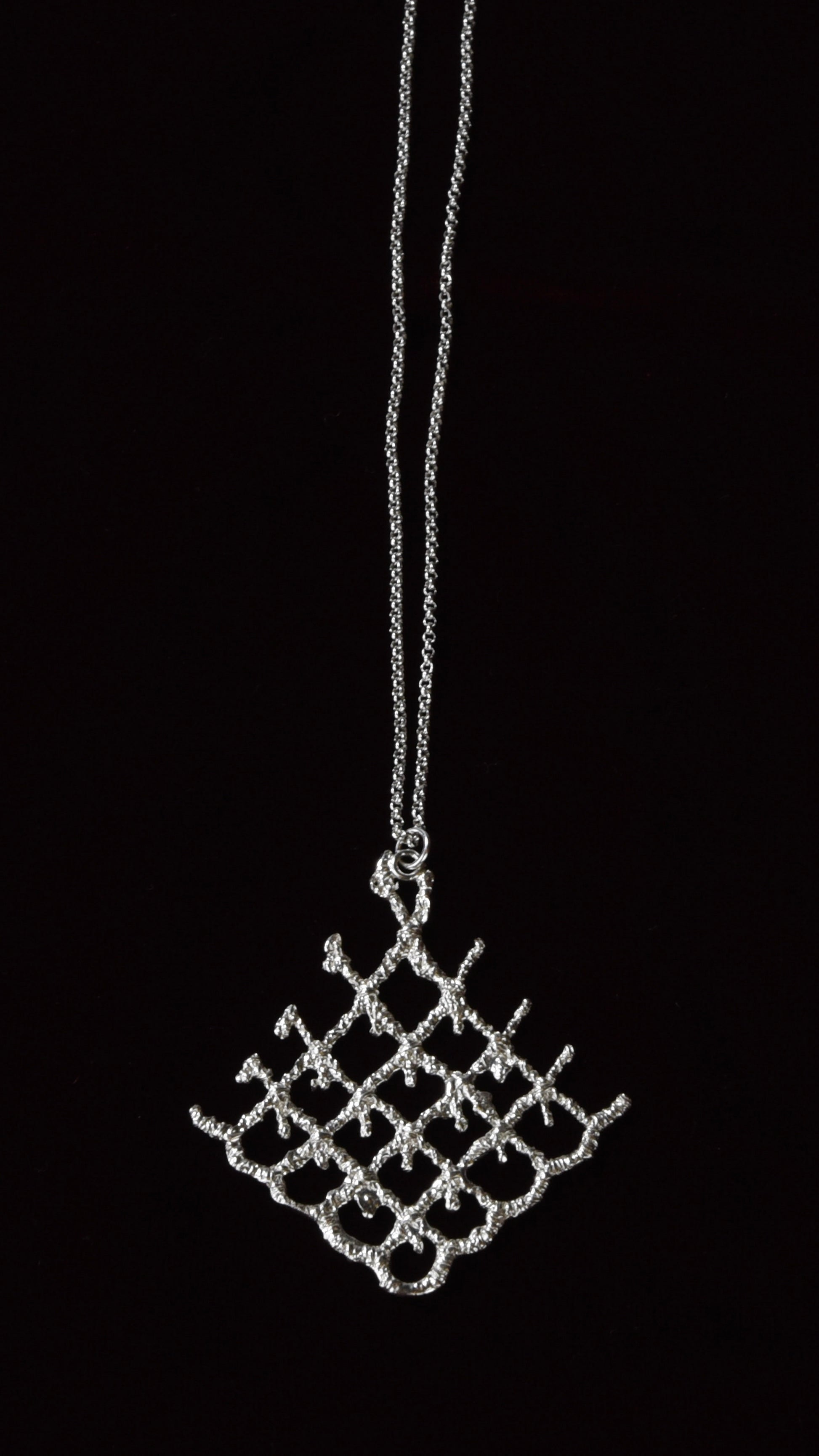 Silver lattice pendant necklace on a black background