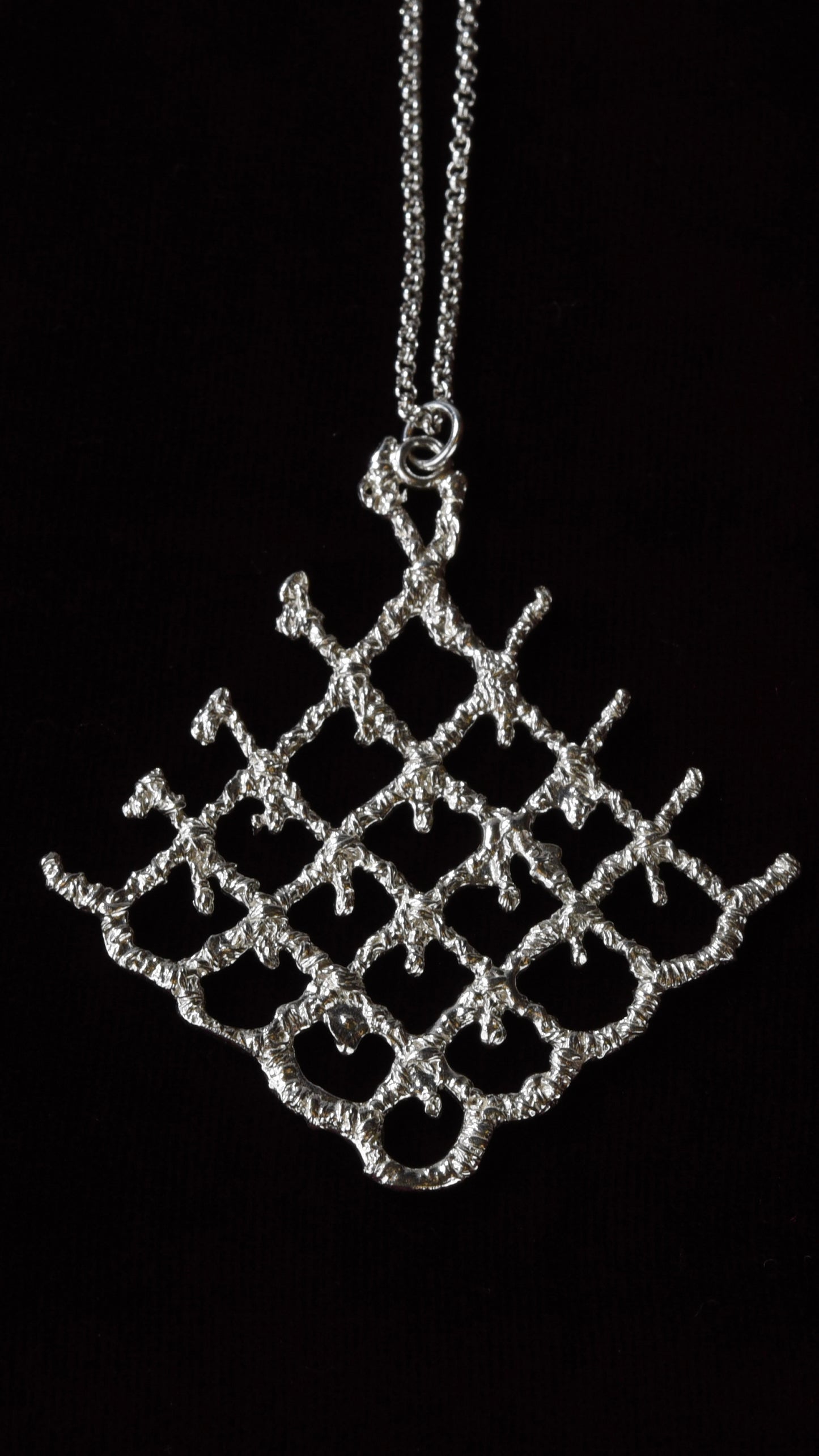 Silver lattice pendant necklace on a black background
