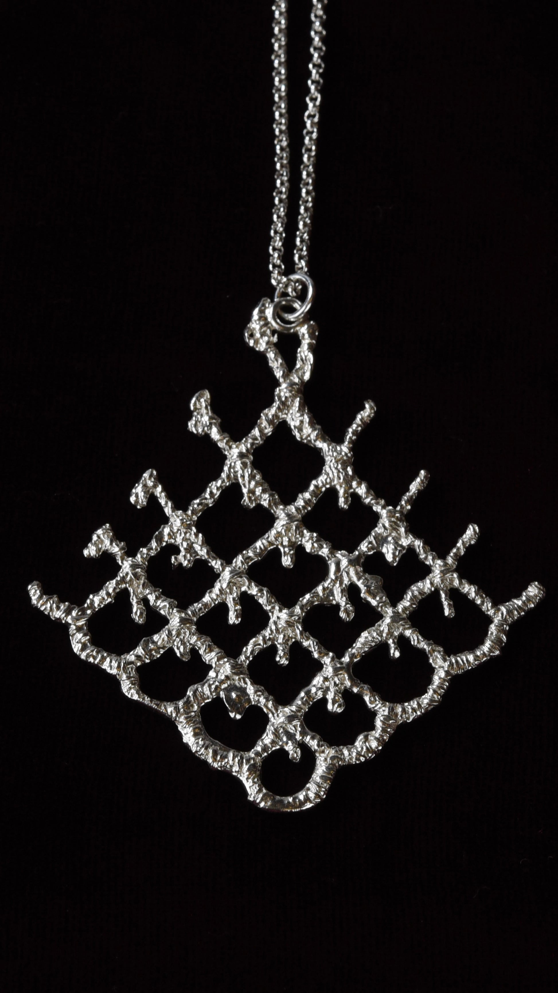 Silver lattice pendant necklace on a black background
