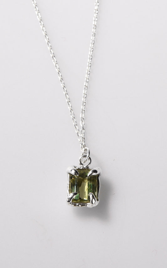 Silver necklace with a green gemstone pendant on a light gray background
