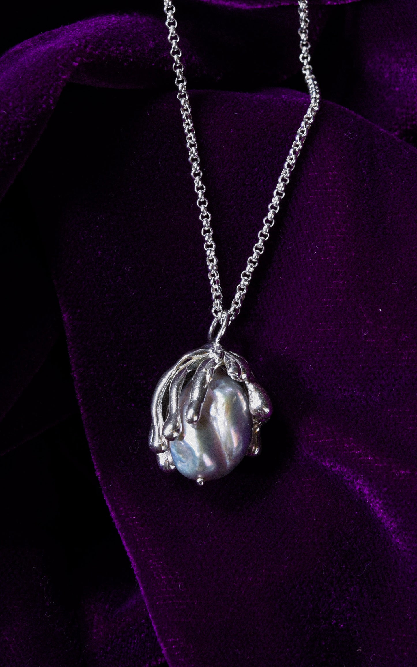 Organic sea inspired handmade sterling silver pendant with baroque pearl on a purple velvet background
