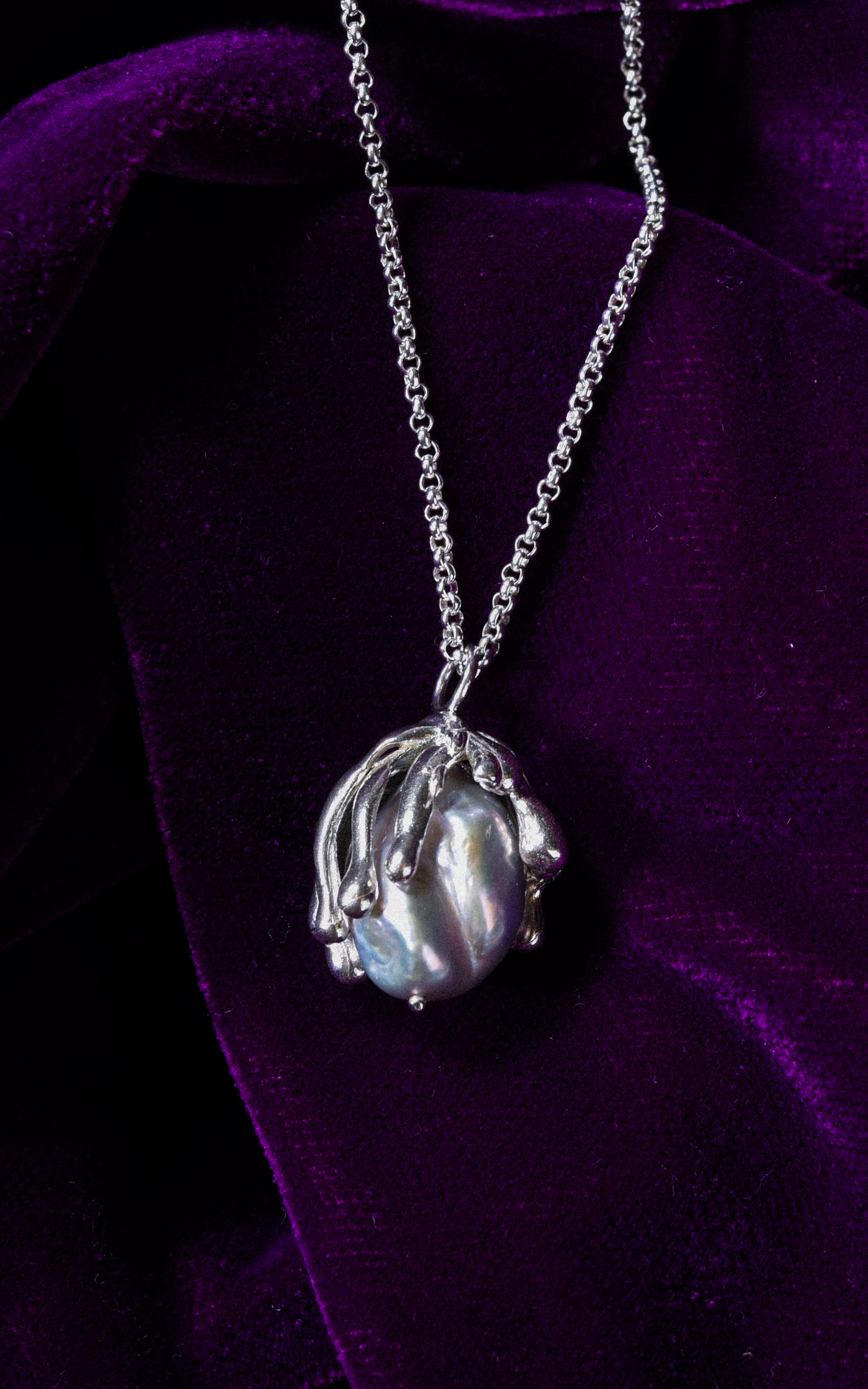 Organic sea inspired handmade sterling silver pendant with baroque pearl on a purple velvet background
