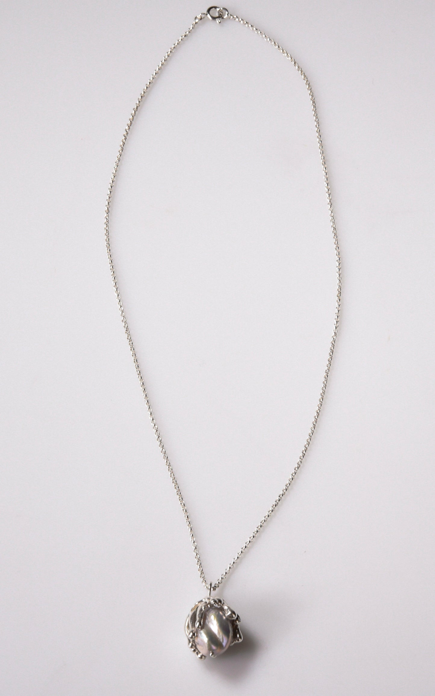 Organic sea inspired handmade sterling silver pendant with baroque pearl on light gray background
