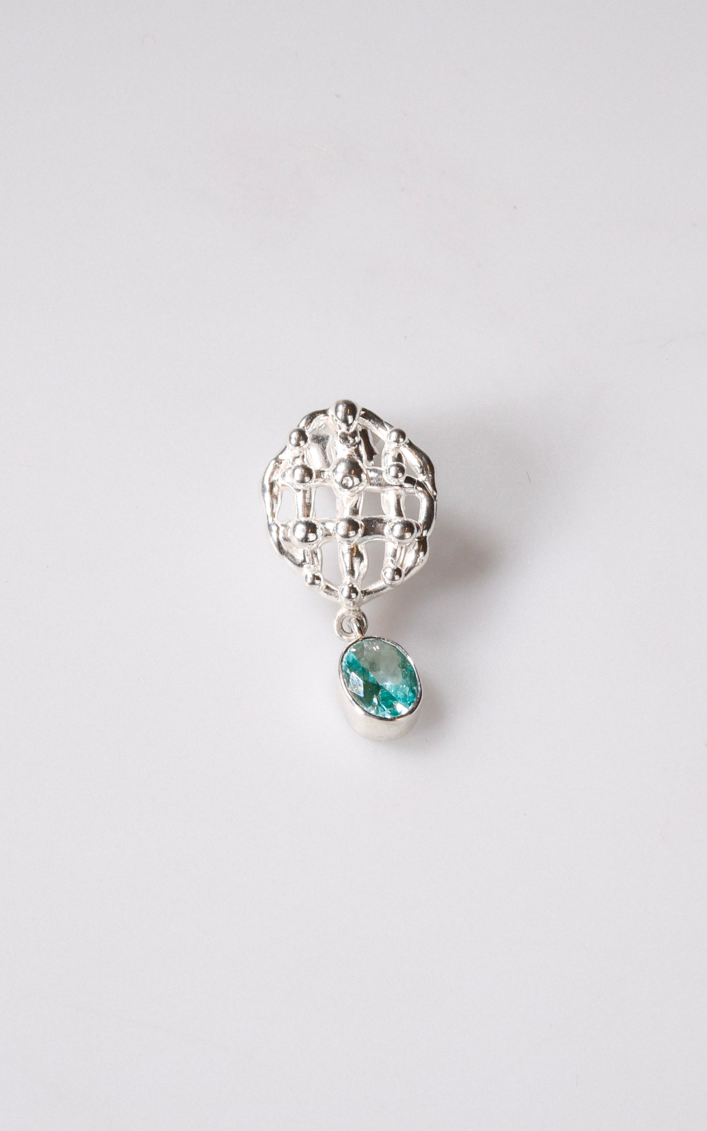 Silver earring with a turquoise oval gemstone on a light gray background
