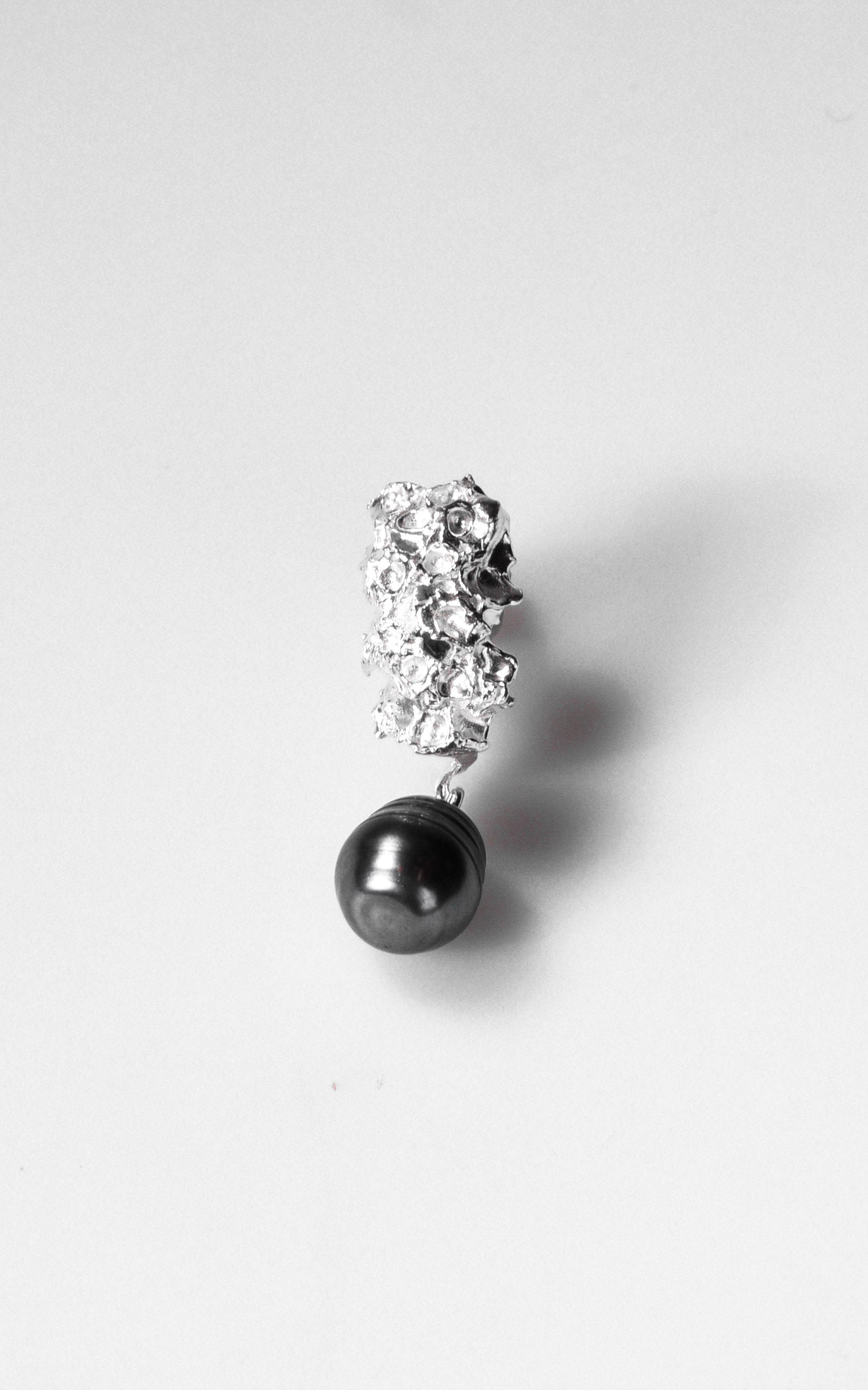 Earring with a black pearl and small flower elements on a white background