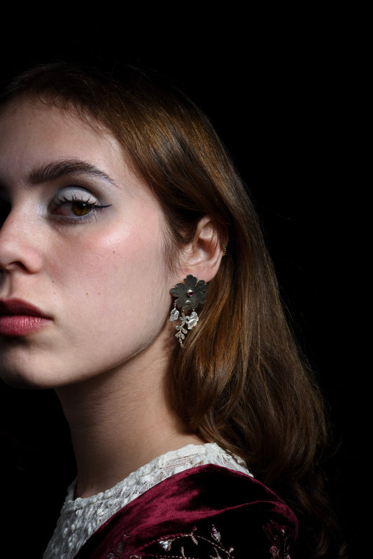 Close-up of a woman wearing handmade silver earrings with a dark background